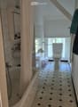 Bathroom with a bathtub, toilet, sink, and shower curtain. The floor has a patterned tile design, and there is a small window providing natural light.