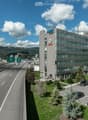 A multi-story office building with the Notz logo on the facade, surrounded by a parking lot and a highway with multiple lanes of traffic.