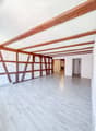 Empty room with wooden beams on the ceiling, white walls, and light wooden flooring. No furniture or equipment is present.