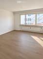 Empty room with wooden flooring, white walls, large windows, and a radiator. No furniture or equipment present.