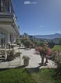 Well-maintained garden with a patio area, outdoor furniture, potted plants, and a scenic mountain view in the background.