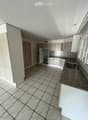 Modern kitchen with white cabinets, granite countertop, tiled floor, and stainless steel sink.