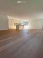 Empty room with wooden flooring, white walls, and large windows. No furniture or equipment present.