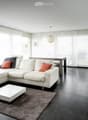 Modern living room with white sectional sofa, coffee table, fireplace, and large windows with blinds.