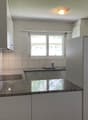 Modern kitchen with granite countertops, white cabinets, stainless steel sink, and a built-in refrigerator.