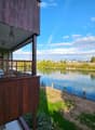 Wooden balcony overlooking a serene river with a scenic view of the surrounding landscape and town.