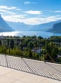 Balcony with a metal railing overlooking a scenic lake and mountain landscape.