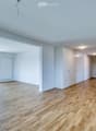 Empty room with wooden flooring, white walls, large windows, and built-in white cabinetry.