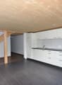 Modern kitchen with white cabinets, dark countertops, and a black tiled floor. Features a wooden staircase leading upwards.