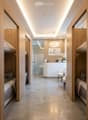 Modern hallway with wooden paneling, recessed lighting, and a reception area visible at the end. Features a sleek, minimalist design with a polished concrete floor and a reception desk with chairs.
