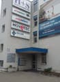 A multi-story building with a brick facade, multiple company signs, and a blue awning over the entrance.