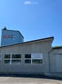Industrial building with a sign reading 'KUNZ', multiple windows, and a smaller building on top