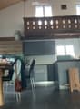 Modern kitchen with wooden table, chairs, stools, grey cabinets, and a wooden balcony railing above.
