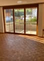 Empty room with wooden herringbone flooring and large sliding glass doors leading to a balcony or outdoor area.