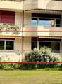 Multi-story residential building with balconies, windows, and greenery.