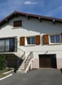 Two-story house with white exterior, wooden shutters, garage, and balcony accessible via stairs.