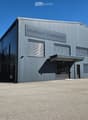 Modern industrial building with a grey metal facade, large windows, and a prominent sign reading "motoactive". Features a large garage door on the left and a covered entrance on the right.