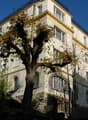 A multi-story building with a balcony on the top floor, surrounded by trees.