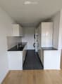 Modern kitchen with white cabinets, black countertops, stainless steel sink, and a washing machine in the background.