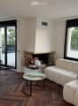 Modern living room with large windows offering a scenic view, a fireplace, a white sectional sofa, and a round coffee table.