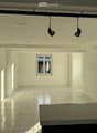 Empty room with white walls, tiled floor, and large windows. No furniture or equipment present.