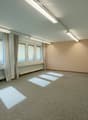 Empty room with carpeted floor, large windows with curtains, and a door. No furniture or equipment present.