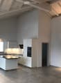 Modern kitchen with white cabinets, a central island, and built-in appliances, featuring large windows and warm lighting.