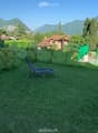 Well-maintained garden with green grass, lounge chairs, and a scenic mountain view in the background.