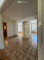 Empty room with tiled floor, white walls, and several open doors leading to other rooms.