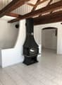 Hallway with exposed wooden beams, a black fireplace, and a staircase leading upwards.