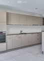 Modern kitchen with light grey cabinets, stainless steel oven, and a black countertop.