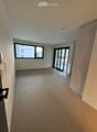 Empty room with concrete floor, white walls, large window, and sliding glass door leading outside.