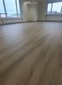 Empty room with wooden flooring, large windows, and white walls.