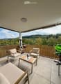 Balcony with a scenic view of a forested area, featuring a tiled floor, a bamboo privacy screen, and a small seating area with chairs and a coffee table.