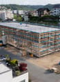 A multi-story building under construction with scaffolding, surrounded by other residential buildings and a crane in the background.