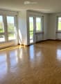 Empty room with wooden flooring, large windows, and radiators along the walls.