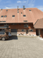 2 story brick house, multiple windows, red roof, cars parked, covered parking, carport