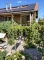 Garden area with a patio, outdoor furniture, umbrella, lounge chair, and lush greenery.
