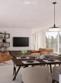 Modern living and dining area with large windows offering a scenic view, featuring a sofa, chairs, dining table, television, bookshelf, and decorative items.
