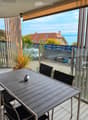 Balcony with a view of the sea, featuring a sofa, a dining table, and chairs.