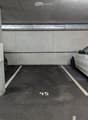 Underground parking area with two parked cars, marked parking spaces, and concrete pillars.
