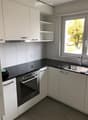 Modern kitchen with white cabinets, black countertops, stainless steel oven, and sink.