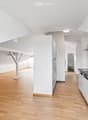 Bright, open kitchen and living area with white walls, wooden flooring, and modern kitchen cabinets.