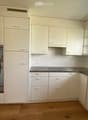 Modern kitchen with white cabinets, stainless steel oven, granite countertop, and wooden flooring.