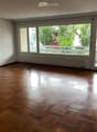 Empty room with wooden flooring, large windows, and sliding glass doors leading to a balcony.