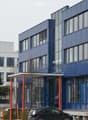 Modern multi-story building with blue and white facade, large windows, and signage for 'Naturstein Beton' and 'Showroom'.