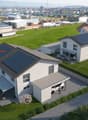 Two-story house with solar panels, a garage, outdoor seating area, garden, swimming pool, and a nearby small house.