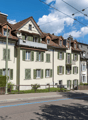 3 story building, brown roof, green shutters, balconies, street view