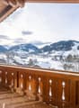 balcony with wooden railing, snowy mountain background, sunlight
