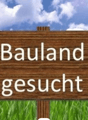 Wooden sign in a field indicating that 'Bauland' (land) is 'gesucht' (wanted)